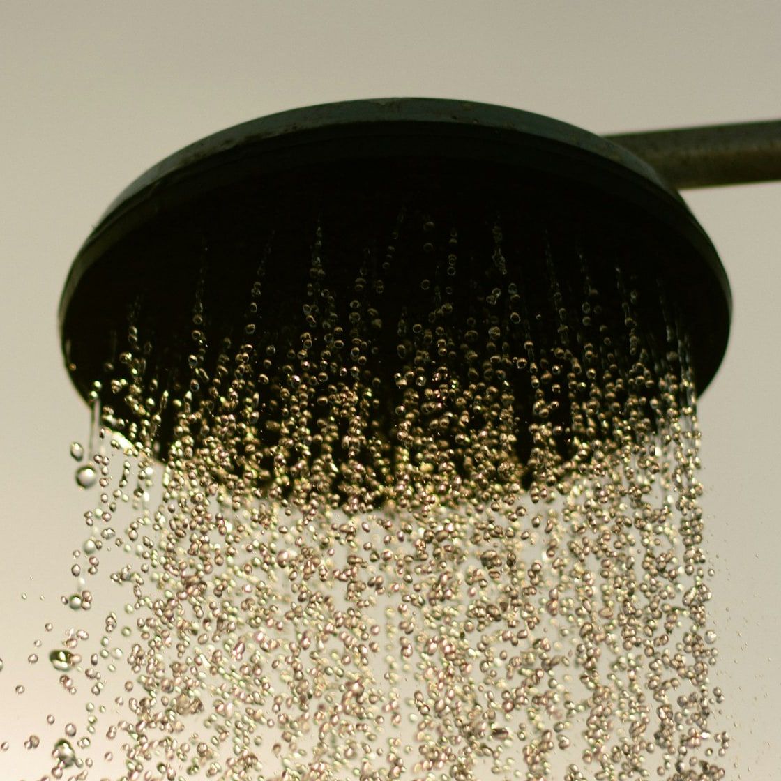 Schwarze runde Regenbrause, aus der Wasser fällt